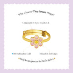 Tiny Jewels gold ring with a pink flower design on a light purple background