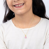Tiny Jewels Child wearing a gold necklace with a pink pendant on a white background