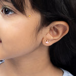 Tiny Jewels close-up of a person wearing a small crown-shaped earring.