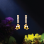 Tiny Jewels gold bee-shaped earrings with diamond accents on a dark background