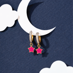Tiny Jewels gold hoop earrings with pink star charms on a blue background with a white crescent moon and cloud.