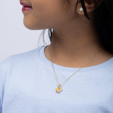 Tiny Jewels Close-up of a person wearing a gold necklace with a colorful pendant against a light background