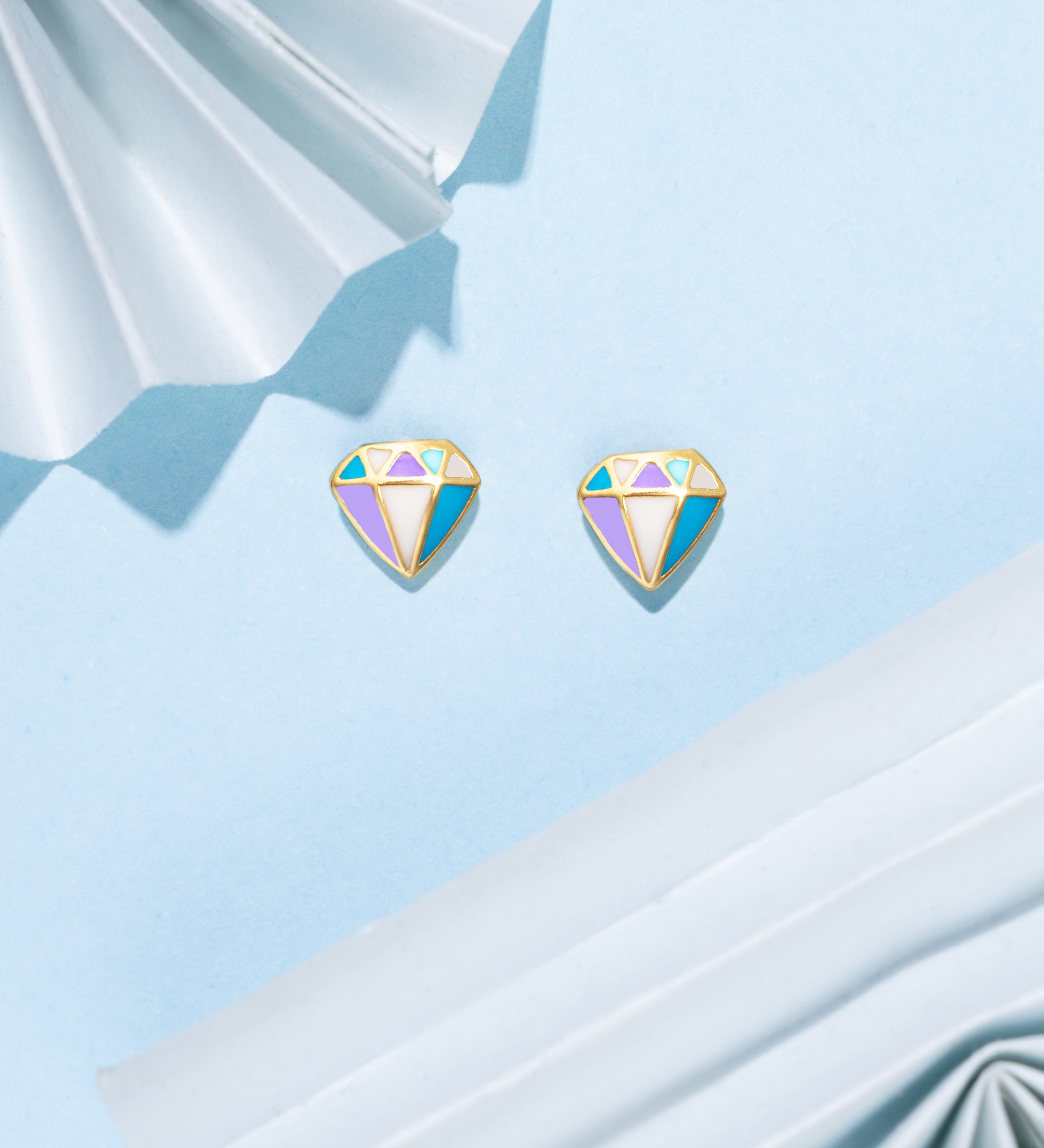 Tiny Jewels colorful gemstone earrings on a light blue fabric background