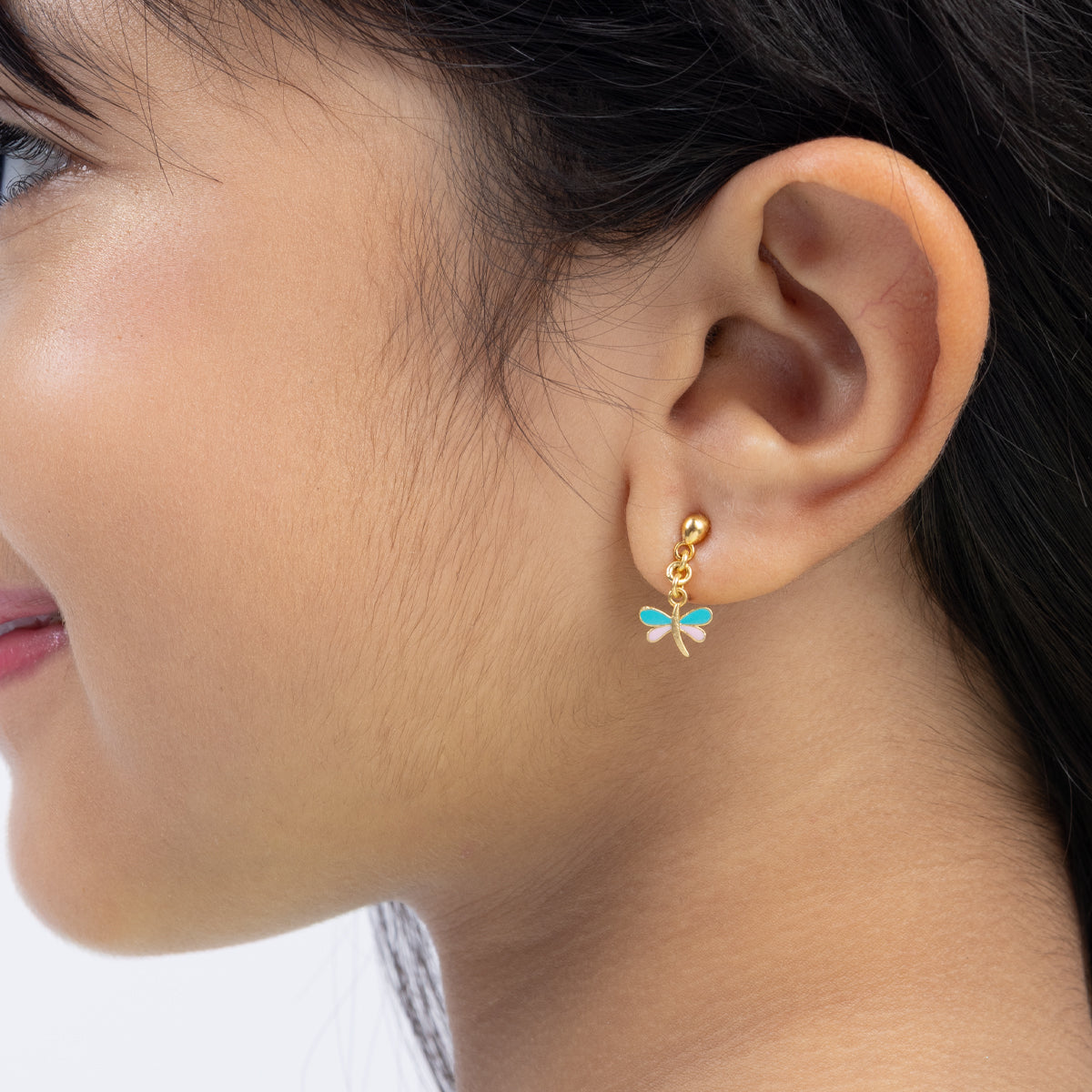 Tiny Jewels close-up of an ear wearing a gold earring with a blue gemstone.