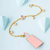 Tiny Jewels gold bracelet with heart-shaped charms on a light blue background