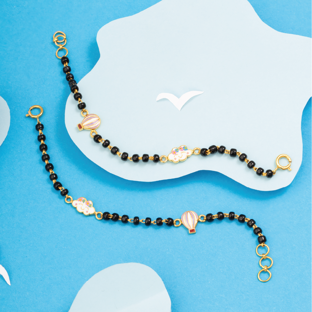 Tiny Jewels black beaded necklace with gold accents on a blue background
