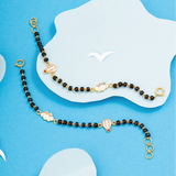 Tiny Jewels black beaded necklace with gold accents on a blue background