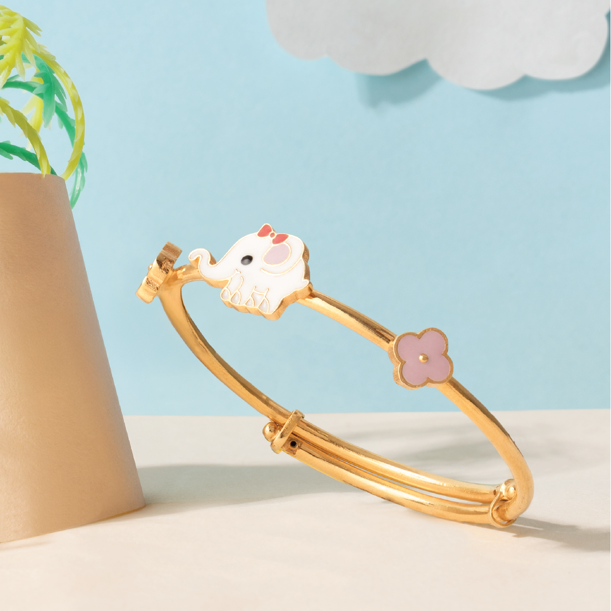 Tiny Jewels gold bracelet with a cat charm on a light blue background