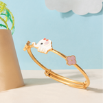 Tiny Jewels gold bracelet with a cat charm on a light blue background