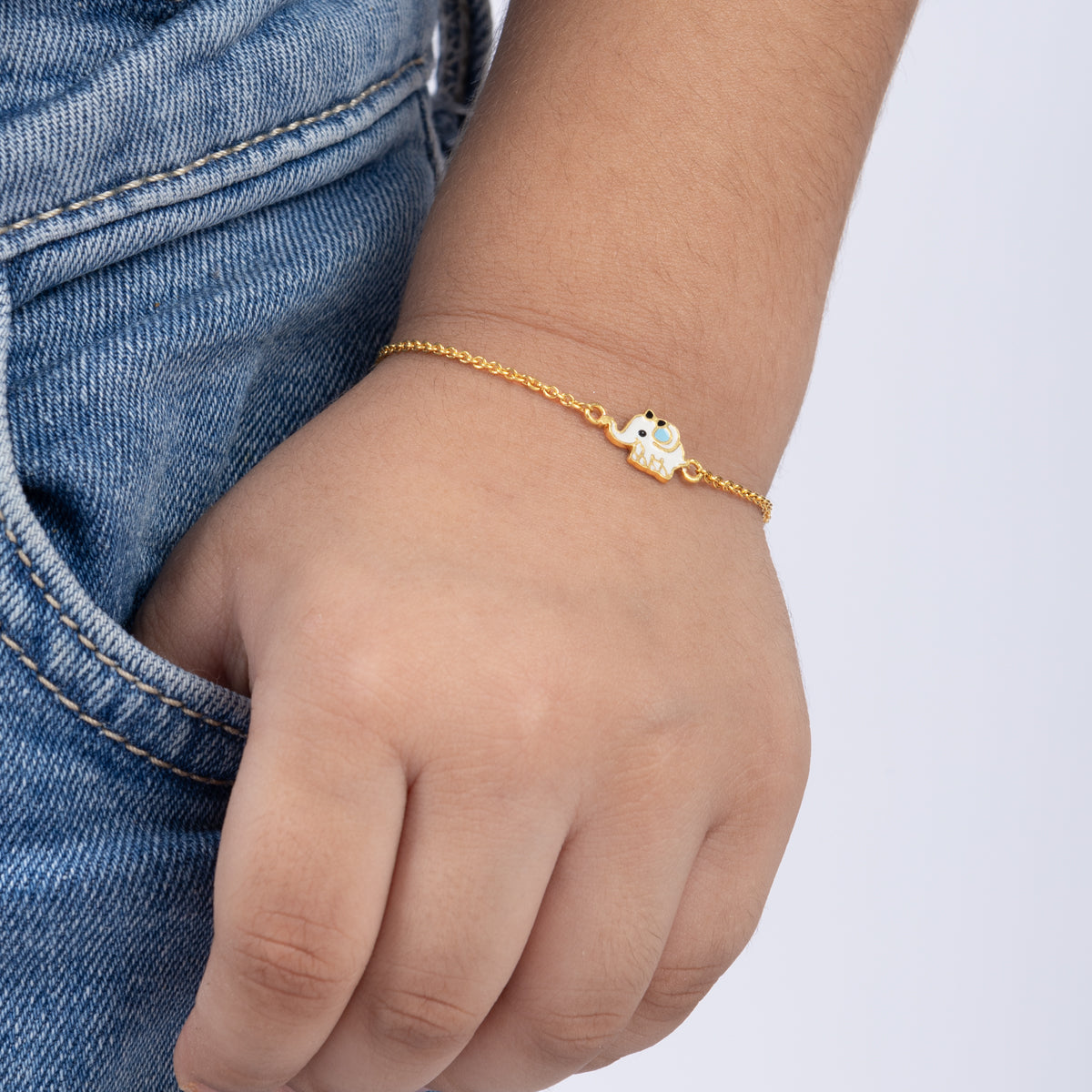 Tiny Jewels gold bracelet with a small owl charm on a child's wrist against a white background