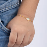 Tiny Jewels gold bracelet with a small owl charm on a child's wrist against a white background