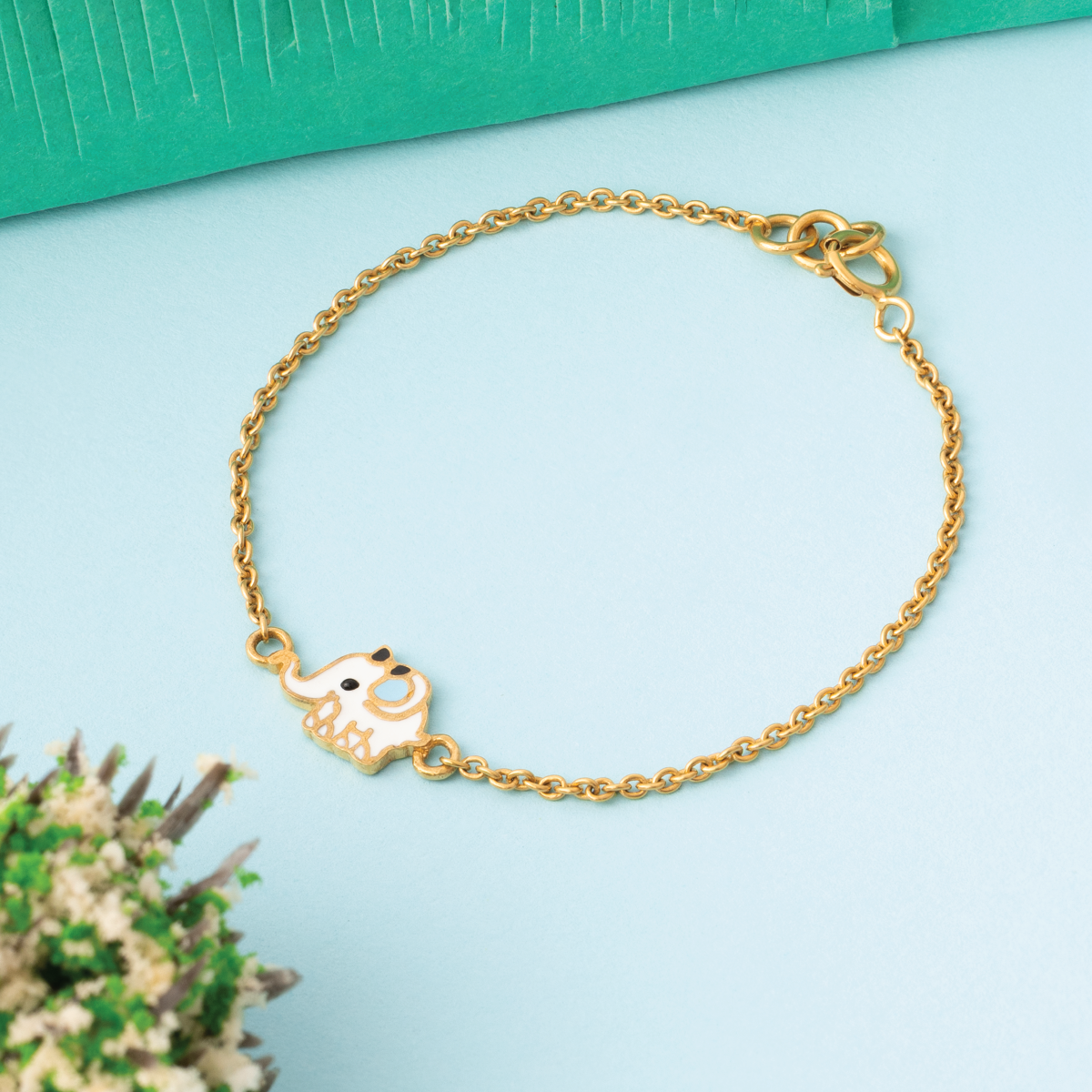 Tiny Jewels gold bracelet with a heart-shaped charm on a light blue background