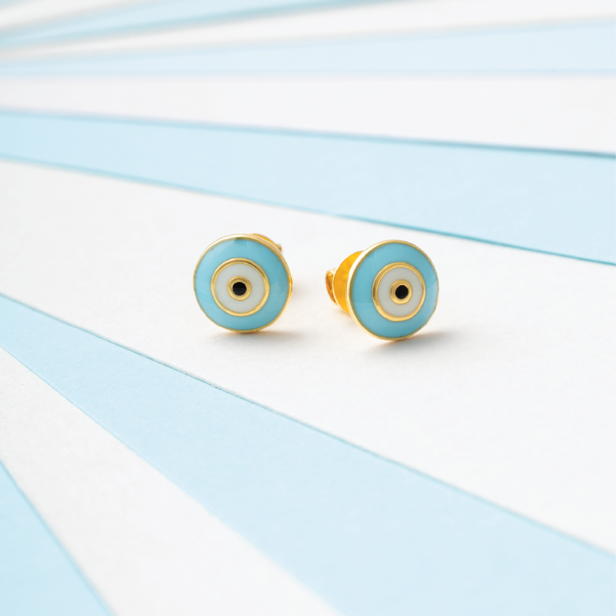 Tiny Jewels pair of turquoise and gold earrings on a light blue and white striped background