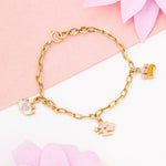 Tiny Jewels gold bracelet with charms on a pink floral background
