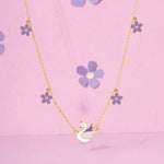 Tiny Jewels necklace with a swan pendant and flower-shaped pendants on a pink background
