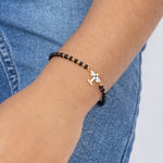 Tiny Jewels bracelet with airplane charm on a wrist against a denim background