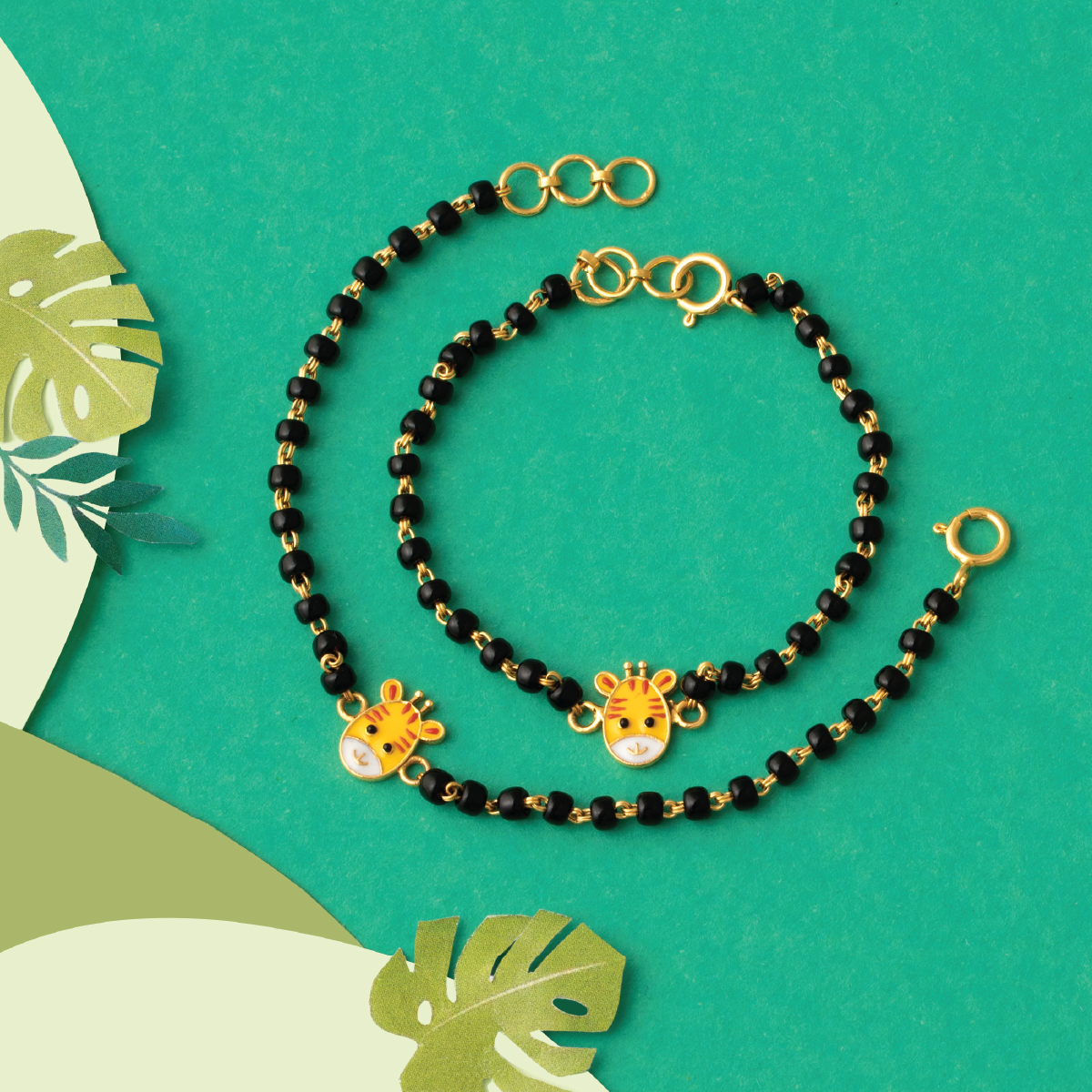 Tiny Jewels black beaded necklace with gold accents on a green background