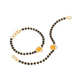 Tiny Jewels black beaded necklace with gold chain and charms on a white background
