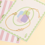 Tiny Jewels gold bracelet on a decorative card with pastel colors