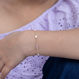 Tiny Jewels person wearing a bracelet with heart and infinity symbol on a purple and blue background