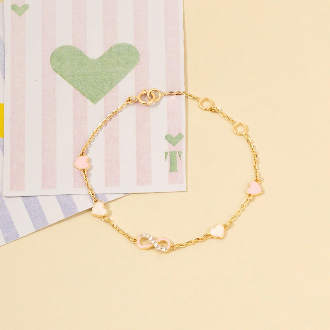 Tiny Jewels gold bracelet with heart-shaped beads on a yellow background