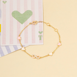 Tiny Jewels gold bracelet with heart-shaped beads on a yellow background