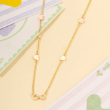 Tiny Jewels gold necklace with heart and infinity symbol charms on a colorful background
