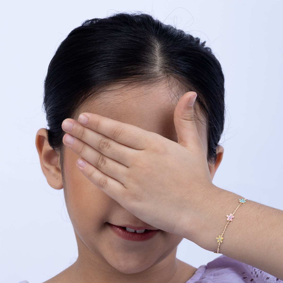 Tiny Jewels child covering their face with a hand on a white background