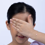 Tiny Jewels child covering their face with a hand on a white background