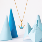 Tiny Jewels gold necklace with a crown pendant on a light blue background