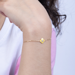 Tiny Jewels gold bracelet with a heart-shaped clasp on a person's wrist against a white background