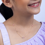 Tiny Jewels close-up of a person wearing a delicate necklace with pink heart pendants on a light background