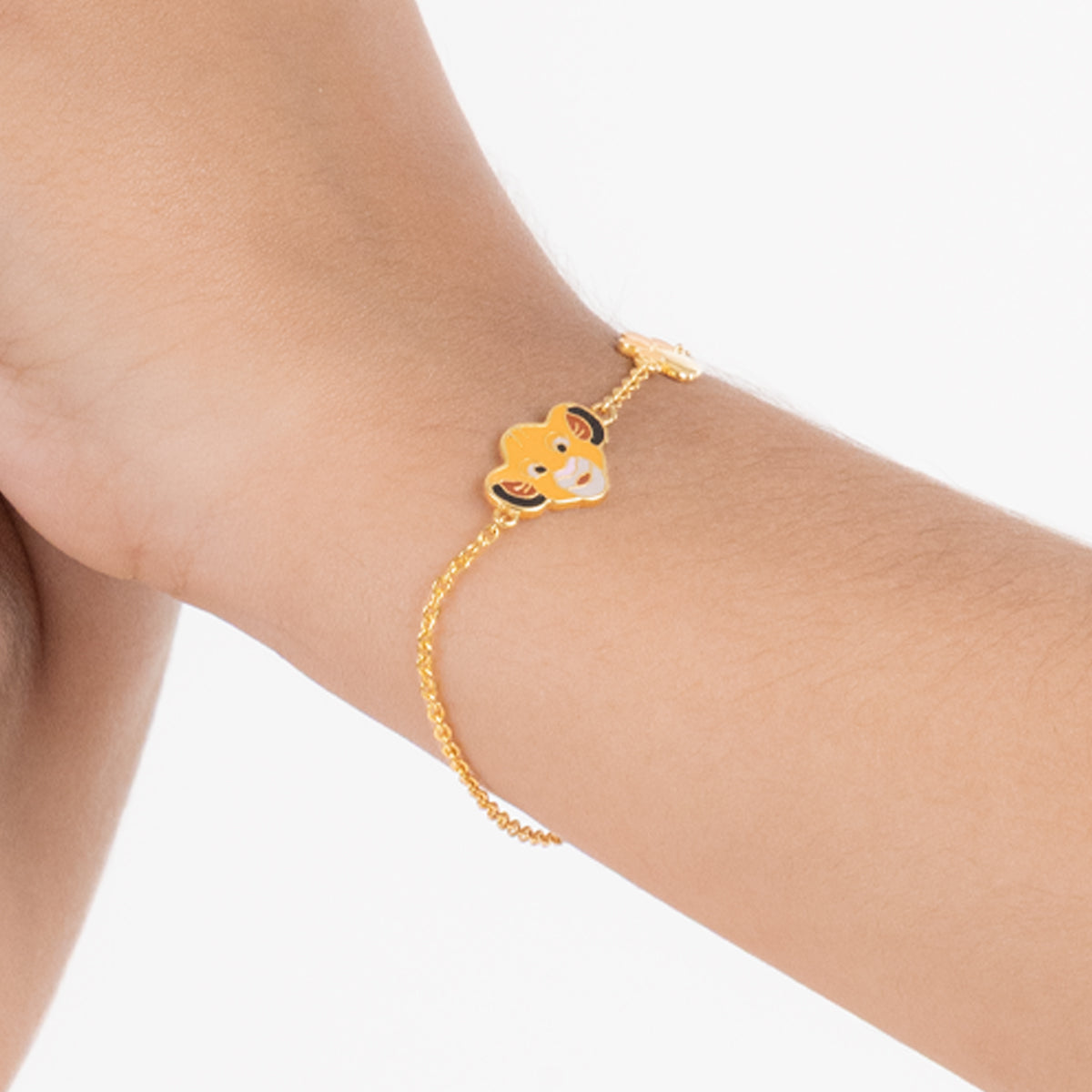 Tiny Jewels gold bracelet with a cartoon character on a person's wrist against a white background
