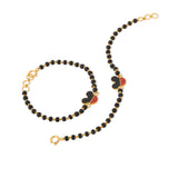 Tiny Jewels black beaded necklace with gold chain and Mickey Mouse head pendants on a white background