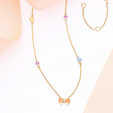 Tiny Jewels gold necklace with colorful beads on a soft pink background