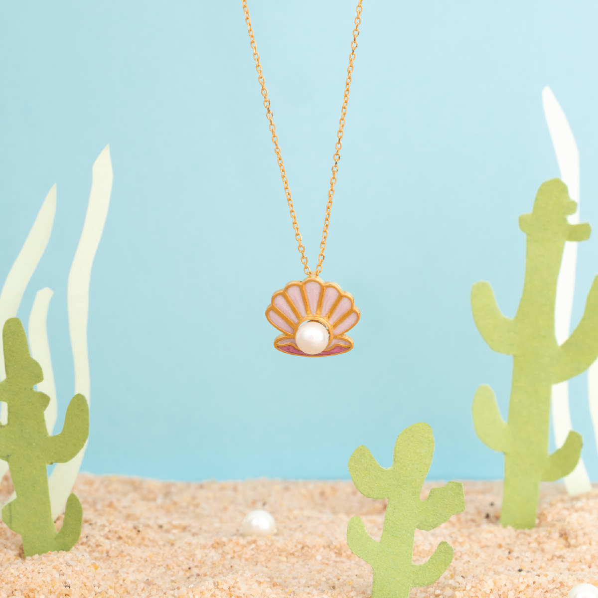 Tiny Jewels necklace with a shell pendant on a beach-themed background