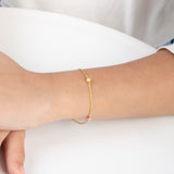 Tiny Jewels gold bracelet on a wrist with a plain background