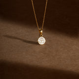 Tiny Jewels gold necklace with a pendant featuring an Om symbol on a brown background