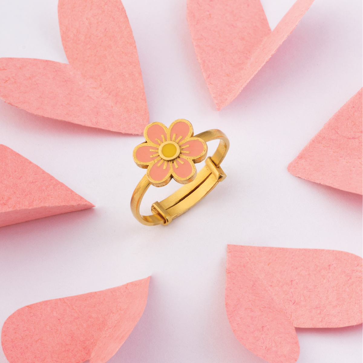Tiny Jewels gold ring with a pink flower design on a white background with pink leaf shapes.