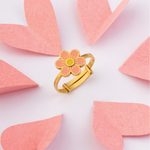 Tiny Jewels gold ring with a pink flower design on a white background with pink leaf shapes.