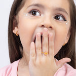 Tiny Jewels young girl with a surprised expression, covering her mouth with her hand.