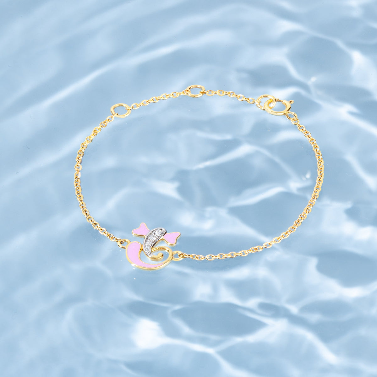 Tiny Jewels gold bracelet with pink heart charm on a water background