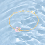 Tiny Jewels gold bracelet with pink heart charm on a water background