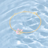 Tiny Jewels gold bracelet with pink heart charm on a water background