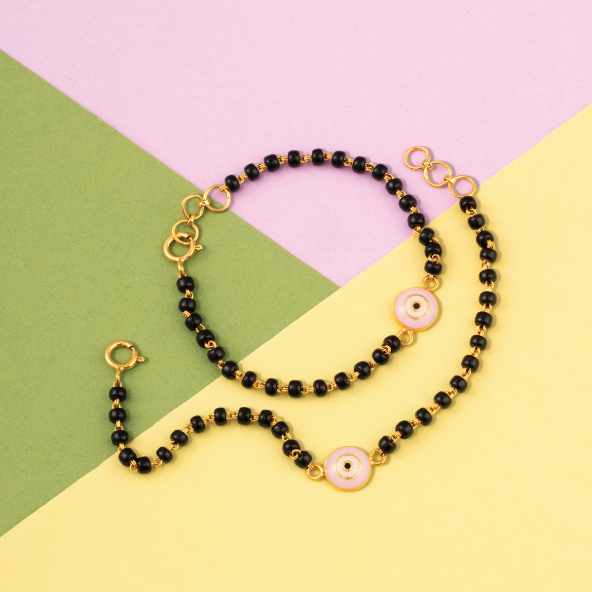 Tiny Jewels necklace with black beads and gold accents on a colorful geometric background
