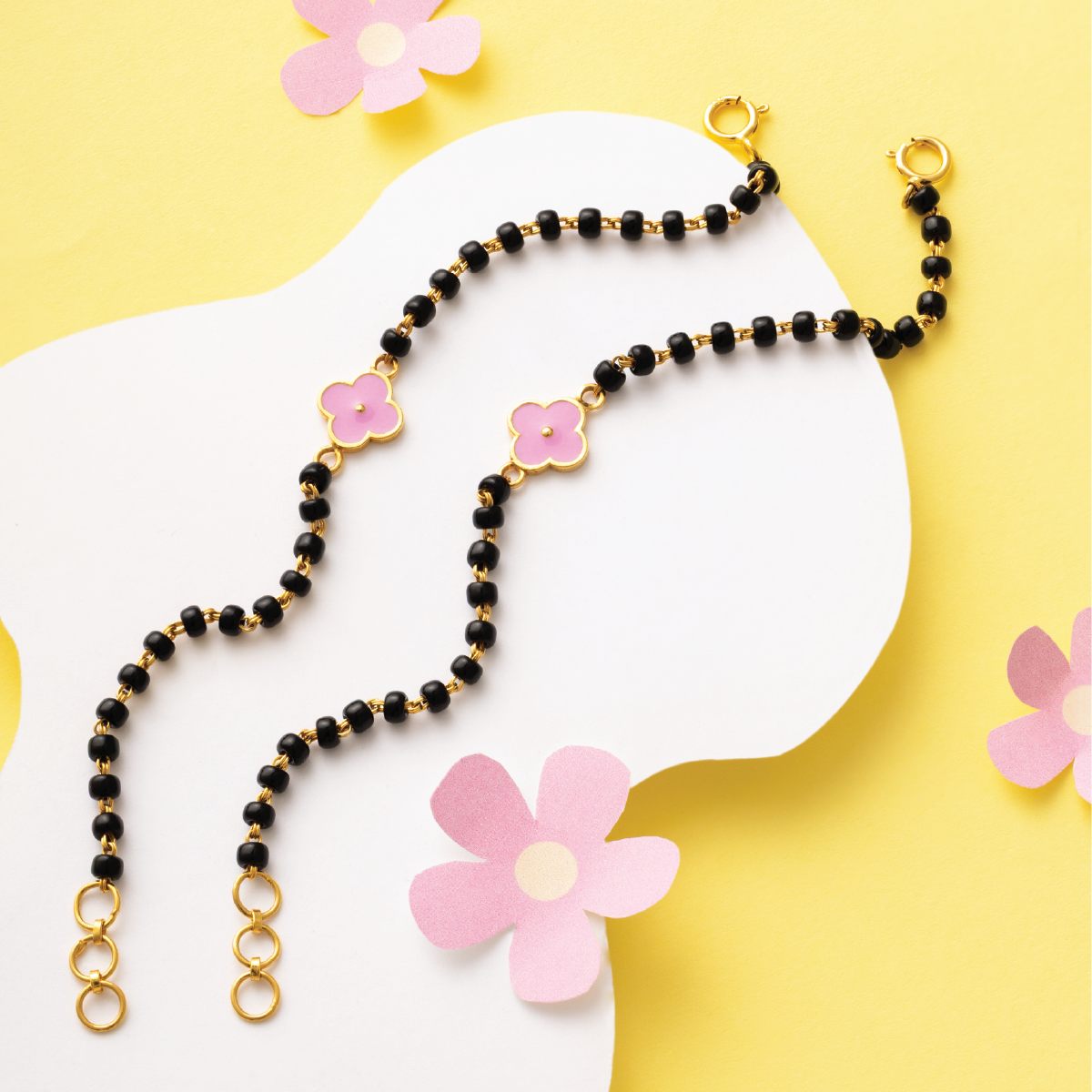 Tiny Jewels black beaded necklace with pink flower charms on a yellow background