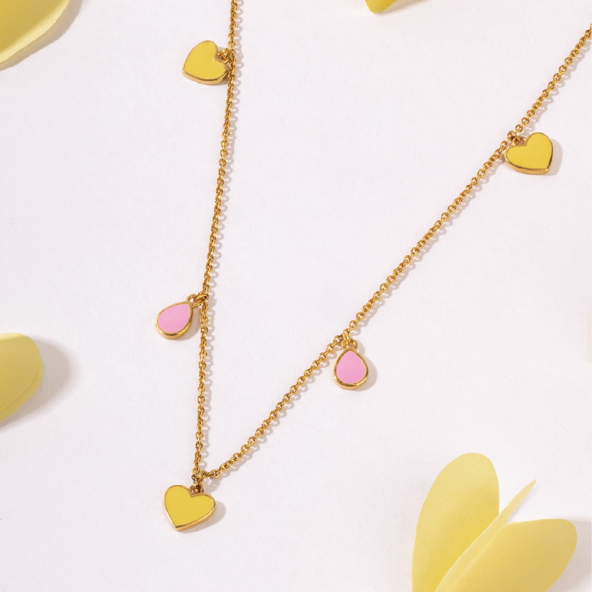 Tiny Jewels gold necklace with heart-shaped pendants on a light background