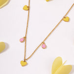 Tiny Jewels gold necklace with heart-shaped pendants on a light background