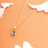 Tiny Jewels gold necklace with an angel pendant on a peach background