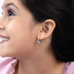 Tiny Jewels close-up of a woman wearing a colorful earring with a neutral background